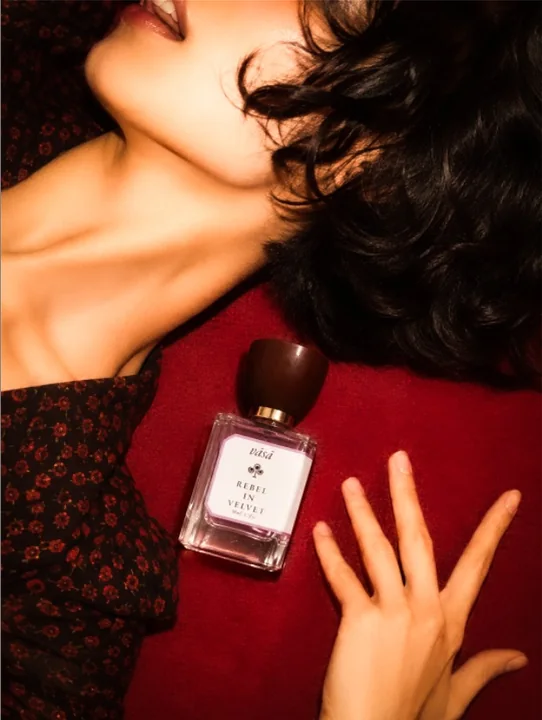 Rebel in Velvet lying on red velvet beside a woman in a floral dress